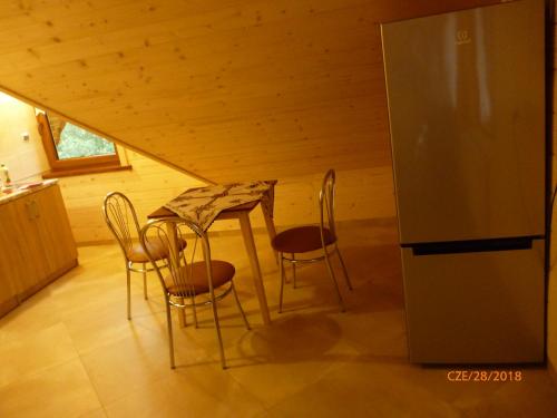 a kitchen with a table and chairs and a refrigerator at Kinga Kulak Pokoje Gościnne in Male Ciche