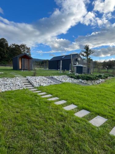 a walkway in the grass next to a barn at Holiday Hill Karpnki, Sauna, Domek Hygge-balia, Domek Lagom-jacuzzi in Karpniki