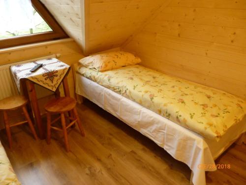 a small bedroom with a bed and a table at Kinga Kulak Pokoje Gościnne in Male Ciche