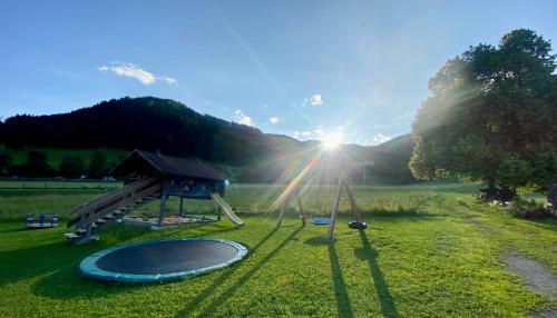 a playground in a field with the sun shining at Chalet Aignerhof in Flachau