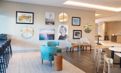 a waiting room with chairs and tables and pictures on the wall at Home2 Suites by Hilton Fort Walton Beach Eglin AirForce Base in Fort Walton Beach
