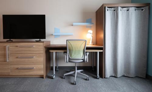 a room with a desk with a television and a chair at Home2 Suites by Hilton Fort Walton Beach Eglin AirForce Base in Fort Walton Beach