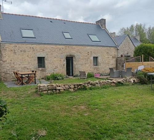a stone house with a picnic table and a bench at Gîte la Korrigane 4 personnes classé 3 étoiles in Pouldreuzic