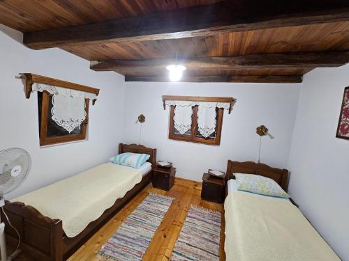 two beds in a room with wooden ceilings and wooden floors at Apartments Kuvarna in Čigoč
