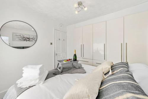 a white bedroom with a bed and a mirror at Lovely 2 Bed Home In Bletchley Milton Keynes in Bletchley