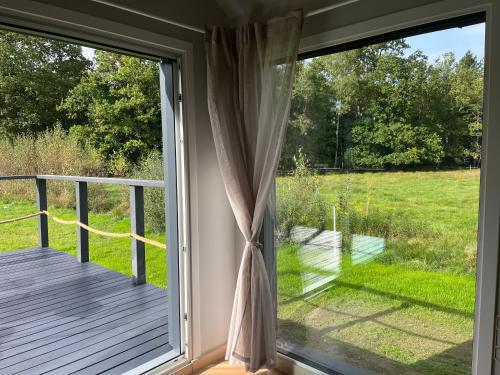 a sliding glass door with a view of a deck at Holiday Hill Karpnki, Sauna, Domek Hygge-balia, Domek Lagom-jacuzzi in Karpniki