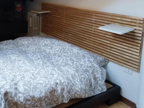 a bedroom with a white bed with a wooden headboard at Studio Meditazione e Yoga in Ossana