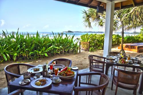 een tafel met borden met voedsel erop met uitzicht op de oceaan bij Weligama Bay Resort in Weligama