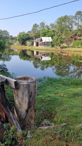 a body of water with a house in the background at Chalé do Lago in Pirapitingui