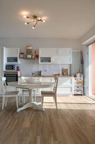 une cuisine blanche avec une table et des chaises dans l'établissement Appartamento Le Coq Vista Mare, à Menton