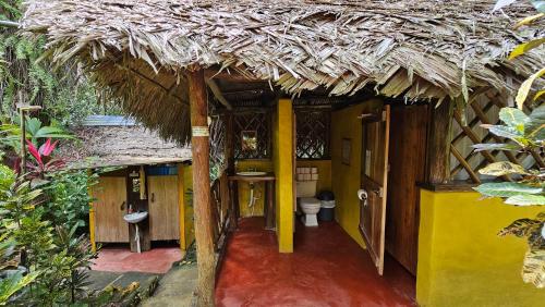 a small bathroom with a toilet and a thatch roof at El Hotelito Perdido in Rio Dulce