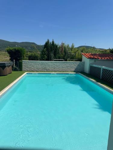une grande piscine bleue devant une maison dans l'établissement Le petit Vialto, à Grospierres