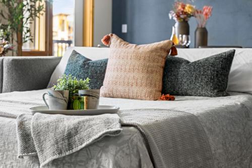 a gray couch with pillows and a tray on it at NEW Spacious MTN View Condo, PRIME location with Hot Tub, Free National Park Pass, Huge Patio, BBQ, Sleeps 7 in Canmore