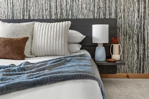 a bedroom with a bed with a blanket and pillows at NEW Spacious MTN View Condo, PRIME location with Hot Tub, Free National Park Pass, Huge Patio, BBQ, Sleeps 7 in Canmore