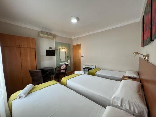 a hotel room with three beds and a desk at Pensión Laforja in Barcelona