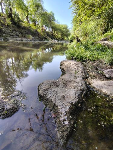 a river with a large rock in the water at Andamundos Hostel in Mina Clavero