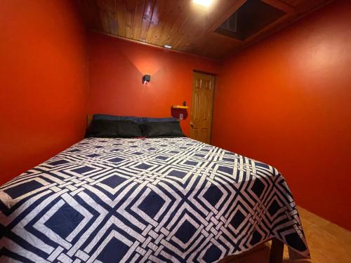 a bedroom with a bed with an orange wall at Residencial Don Santiago in Talca