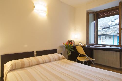 a bedroom with a bed and a desk and a window at Altavilla Locanda E Tipica Trattoria in Bianzone
