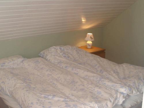an unmade bed in a bedroom with a lamp on a table at 5 person holiday home in LÖNASHULT-By Traum in Torne