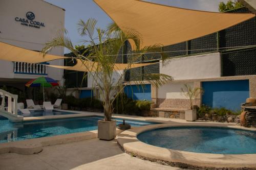 einem Pool mit einer Palme vor einem Gebäude in der Unterkunft Casa Coral in Los Cóbanos