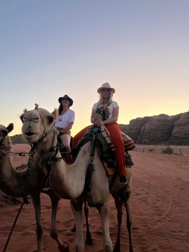zwei Frauen reiten auf Kamelen in der Wüste in der Unterkunft Magic mountains rum in Disah