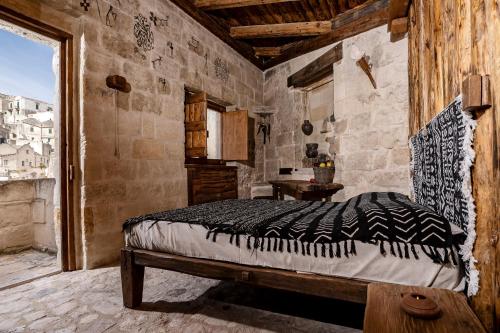 a bedroom with a bed in a stone wall at MOYSEION Matera - Immersion in a distant past in Matera