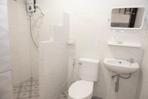 a white bathroom with a toilet and a sink at Bkk39 Airport hotel in Ban Khlong Prawet