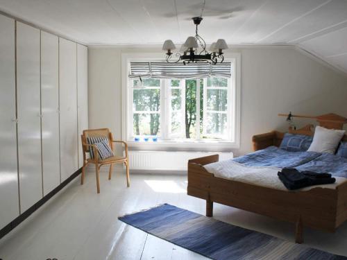 sypialnia z łóżkiem, krzesłem i oknem w obiekcie 5 person holiday home in VÄDDÖ-By Traum w mieście Veda
