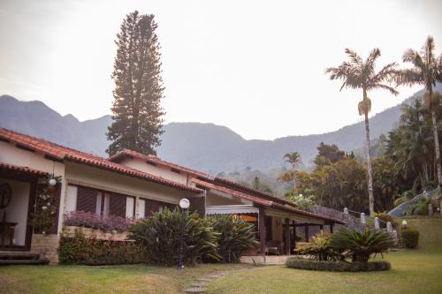 a house with a palm tree and mountains in the background at Recanto dos Vianas in Teresópolis