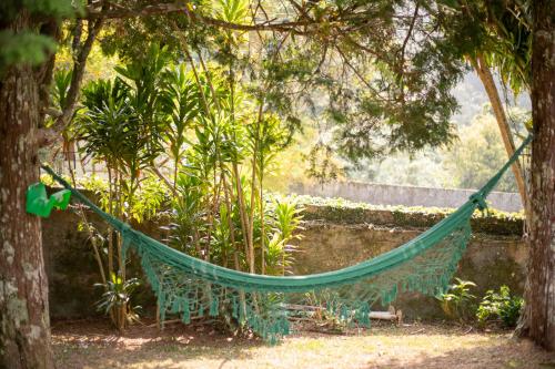 a hammock hanging from a tree in a garden at Recanto dos Vianas in Teresópolis