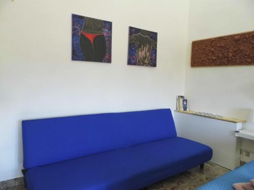 a blue couch in a room with three paintings at Suite 7 turist apartment in Paglieta