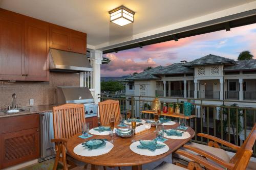 a wooden table on a balcony with a kitchen at Hilton Pool Pass Included, Kolea - Luxe Penthouse, Walk to Beach in Waikoloa