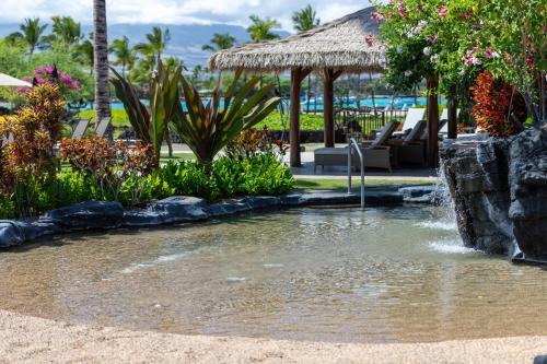 a pond in the middle of a resort at Hilton Pool Pass Included, Kolea - Luxe Penthouse, Walk to Beach in Waikoloa