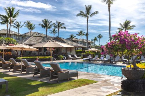 a resort pool with lounge chairs and palm trees at Hilton Pool Pass Included, Kolea - Luxe Penthouse, Walk to Beach in Waikoloa