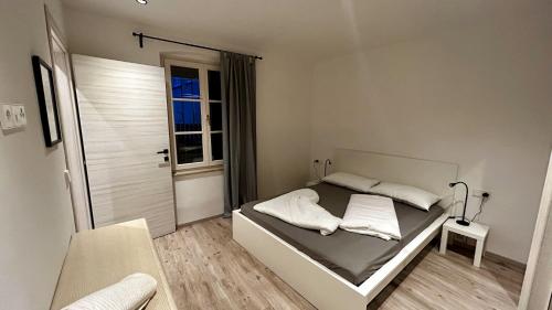 a white bedroom with a bed and a window at Ferienwohnung Julian in Termeno