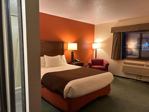 a hotel room with a bed and a chair at Northwoods Inn & Suites - Blackduck in Blackduck
