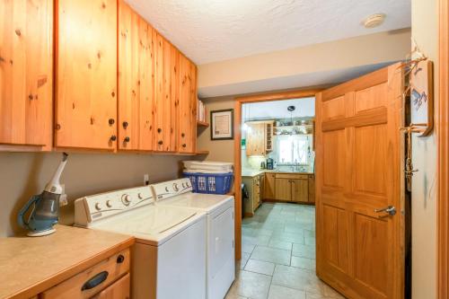 a kitchen with wooden cabinets and a white washing machine at Waterfront Johnson Lake Getaway with Fire Pit! in Johnson Lake