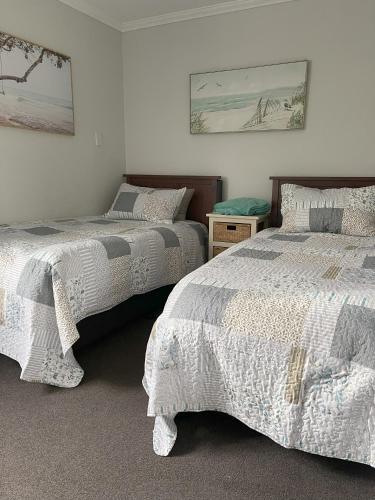 a bedroom with two beds with white comforters at Down South Cottage in Invercargill