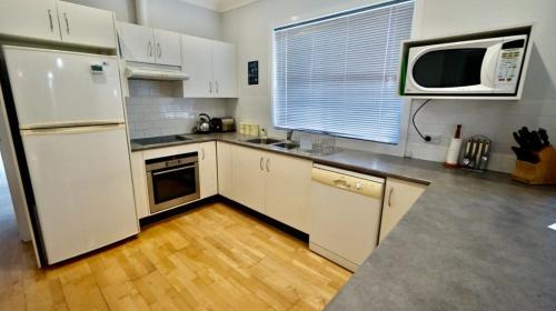 a kitchen with a white refrigerator and a microwave at Serendipity Sands by Experience Jervis Bay in Huskisson