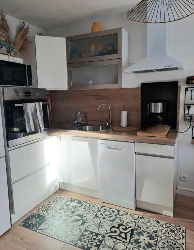 une cuisine avec des armoires blanches et un évier dans l'établissement Appartement cosy proche centre Arles, à Arles