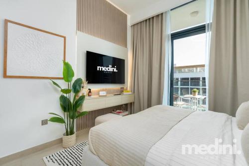 a bedroom with a bed and a tv and a window at 12min from Burj Khalifa - Studio - Azizi Riviera in Dubai