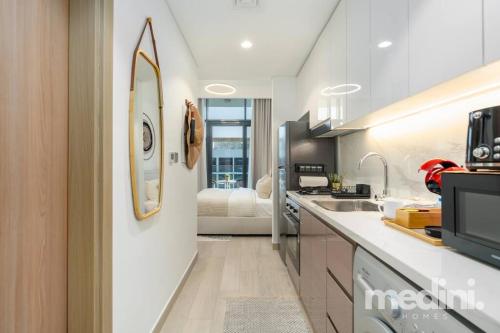 a kitchen with a sink and a room with a bed at 12min from Burj Khalifa - Studio - Azizi Riviera in Dubai
