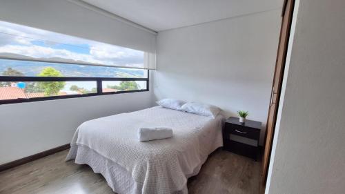 a bedroom with a white bed and a window at Caminos del Dorado sede Apartamento in Guatavita
