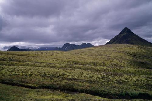 a green field with a mountain in the background at South Coast Panorama in Hvolsvöllur