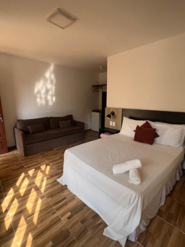 a bedroom with a large white bed and a couch at Pipa Golfinhos Pousada in Pipa