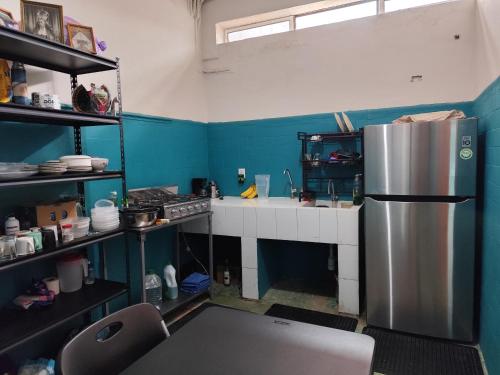 a kitchen with blue walls and a stainless steel refrigerator at Lidia Anturios Hostal in Oaxaca City