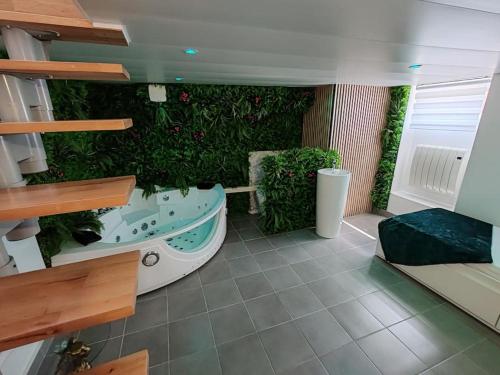 La salle de bains est pourvue d'un mur vert et d'une baignoire. dans l'établissement L'Eden, maison atypique, à Nancy