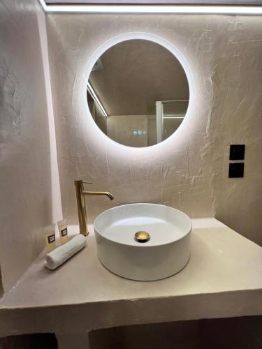 La salle de bains est pourvue d'un lavabo blanc et d'un miroir rond. dans l'établissement Cocon des Moulins, à Toulouse