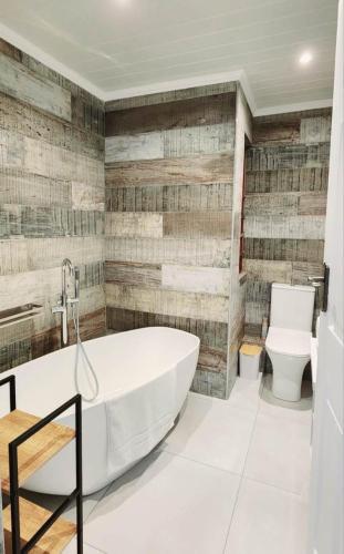 a bathroom with a white tub and a toilet at Sandy Retreat in Mossel Bay