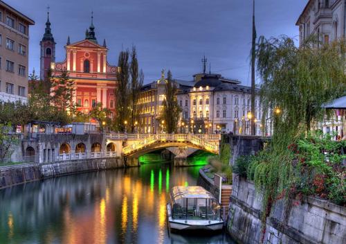 a bridge over a river in a city at night at GOLDEN OASIS Free Private Parking in Ljubljana